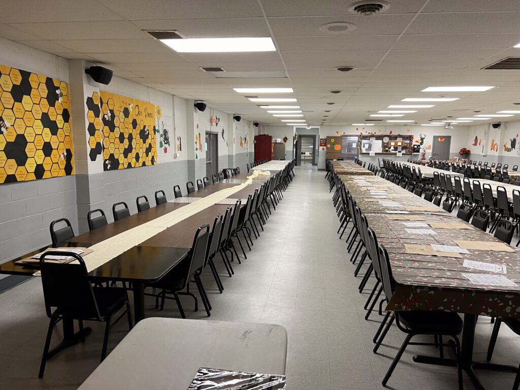 A long room filled with decorated tables and chairs sitting up to the tables.
