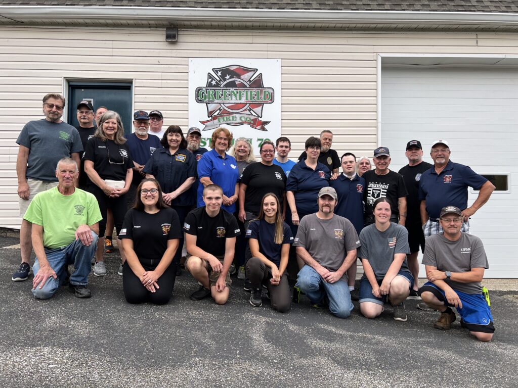 a group of individuals standing in front of a fire department and sign.