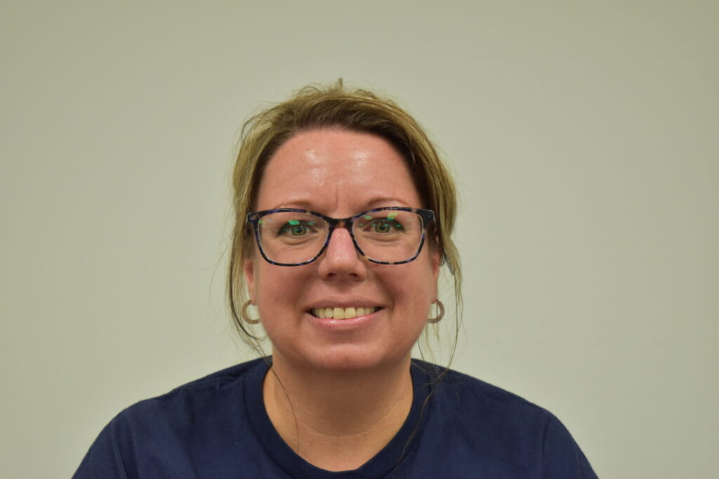 Female in a blue shirt wearing glasses with her hair pulled back