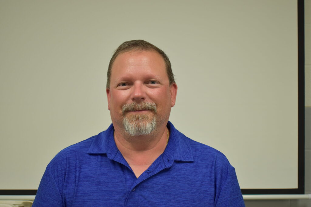 man in blue shirt with a mustache and goatee