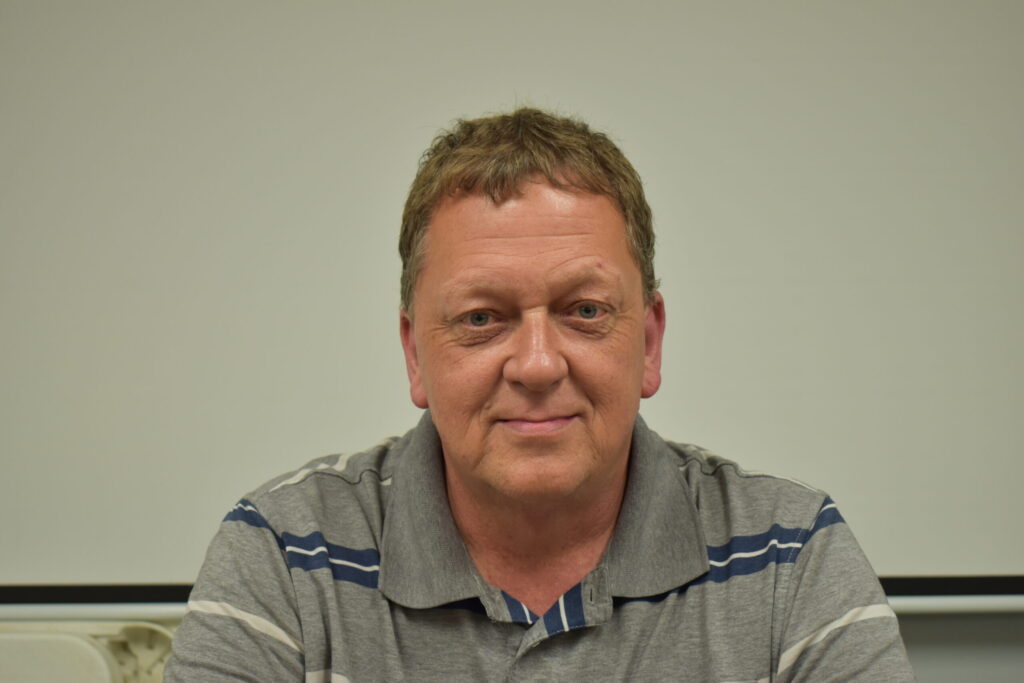 man in a grey and blue striped shirt with short hair