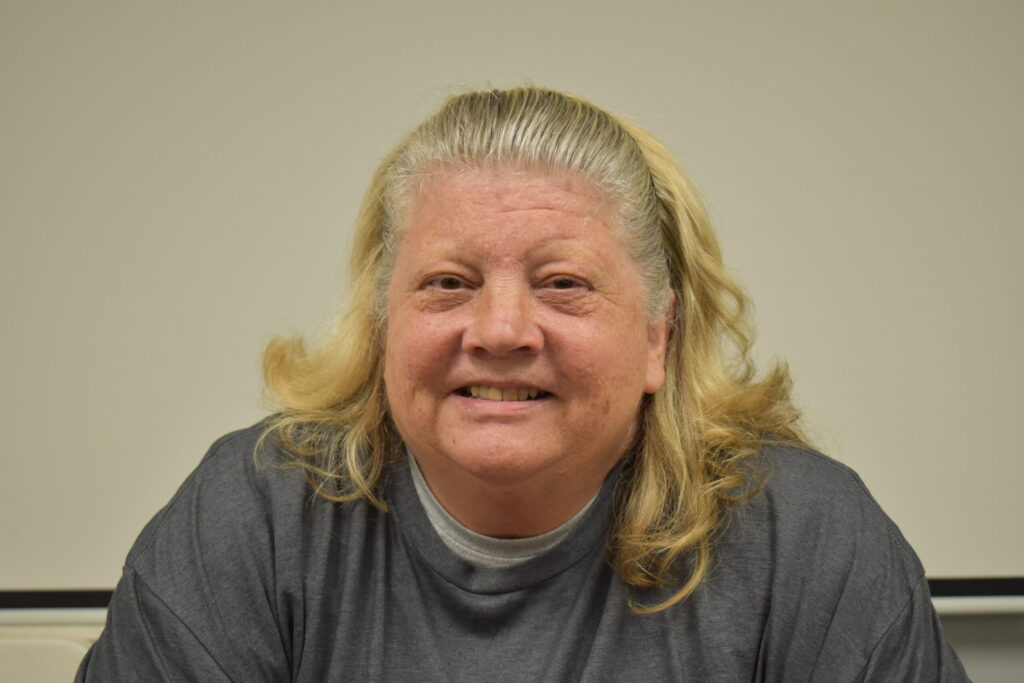 a woman in a grey shirt with longer than shoulder length hair