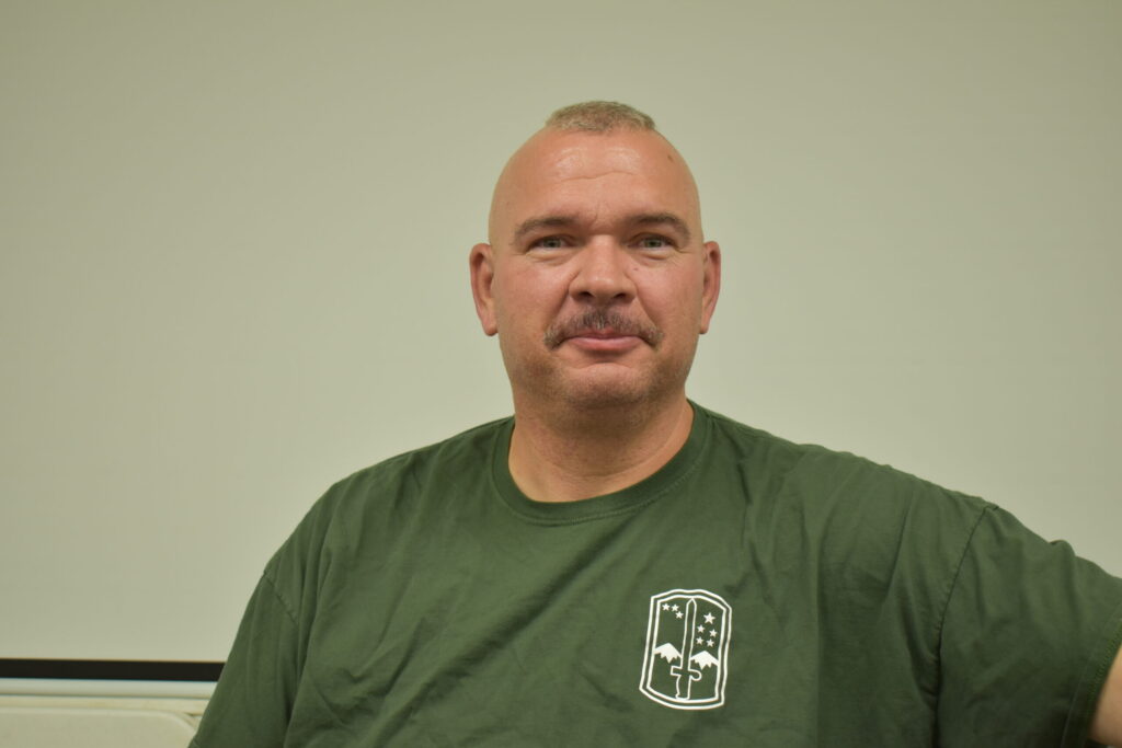 Man in green shirt, a mohawk and a mustache